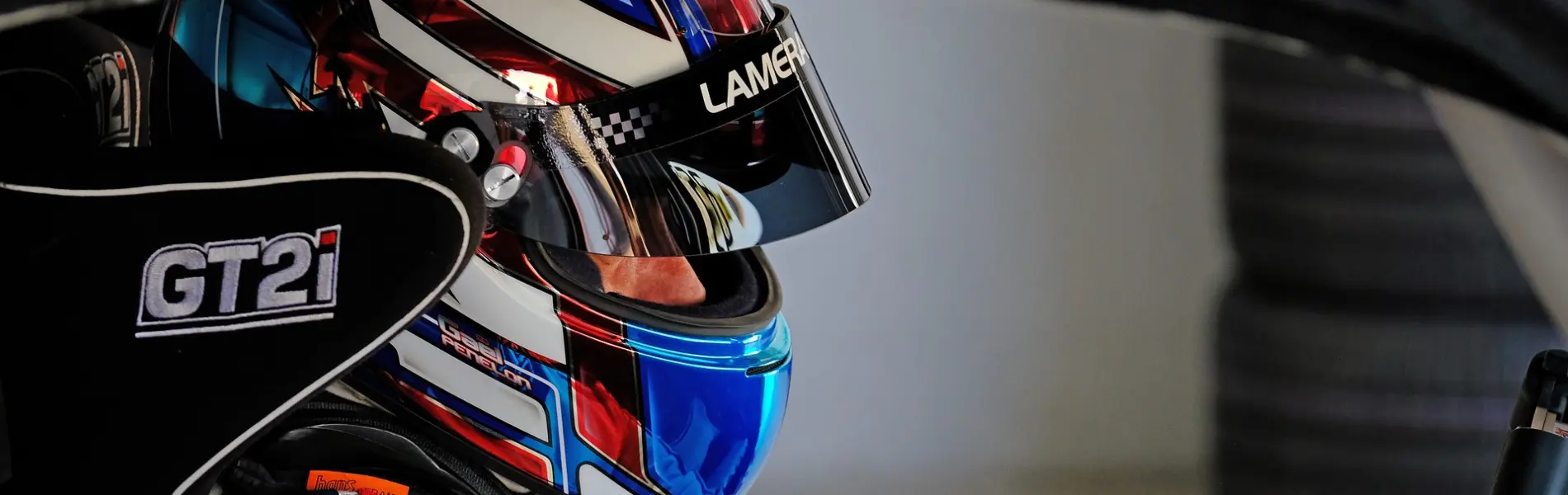 Race car driver wearing full-face helmet in cockpit, focused before competition